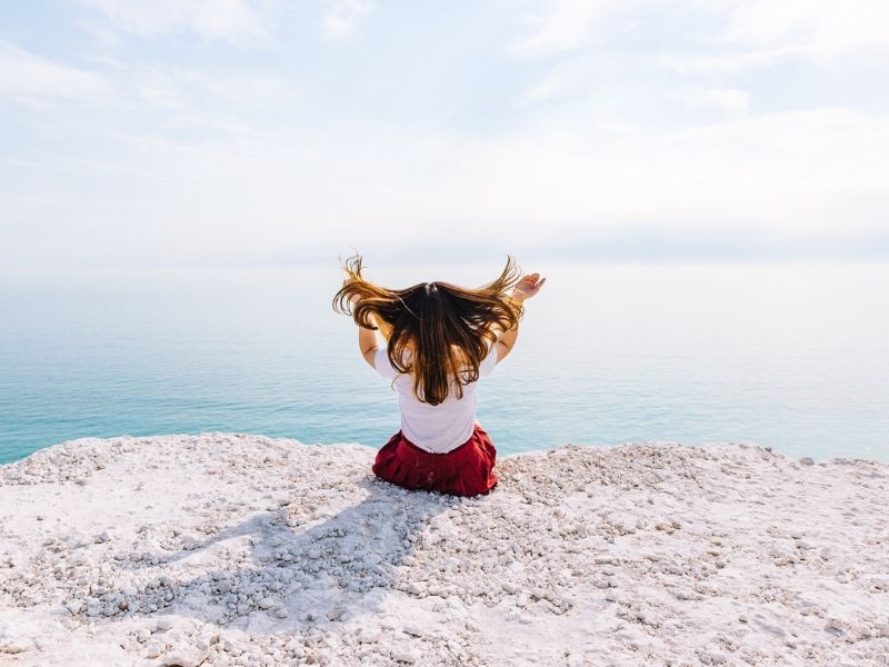 woman sitting on th edge of a cliff in the wind