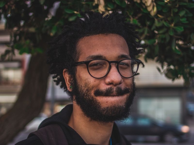 a young man is in close up in front of a tree