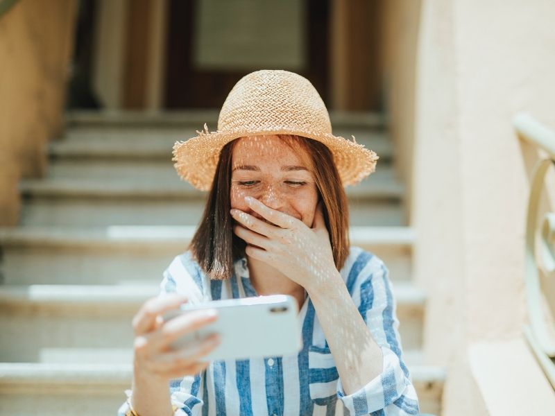 woman is looking at her phone and hiding her amused expression