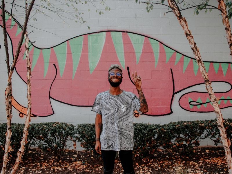 young man standing in front of a painted wall